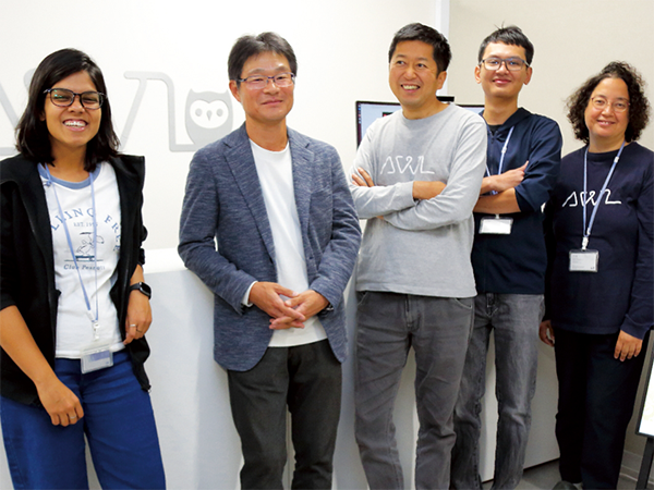 北出氏（右から3番目）と川村教授（右から4番目）を中心に、グローバルに活躍する外国人スタッフたち。多様な文化と視点を持つ人材が、AI開発と技術革新の基盤を支えている